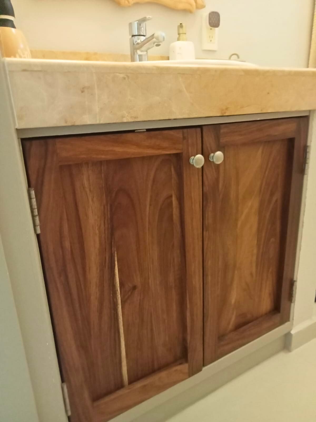 Two-door wood bathroom vanity beneath a stone countertop