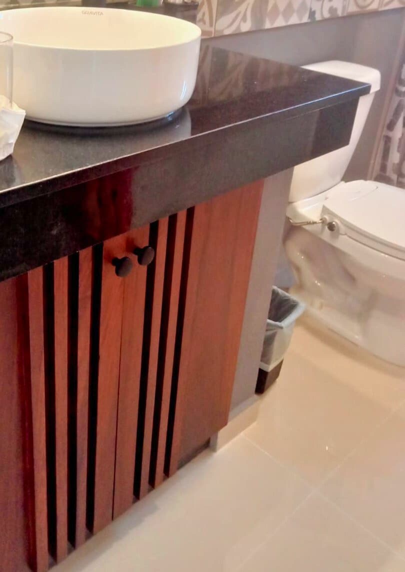 Slatted wood bathroom vanity with vessel sink and dark countertop