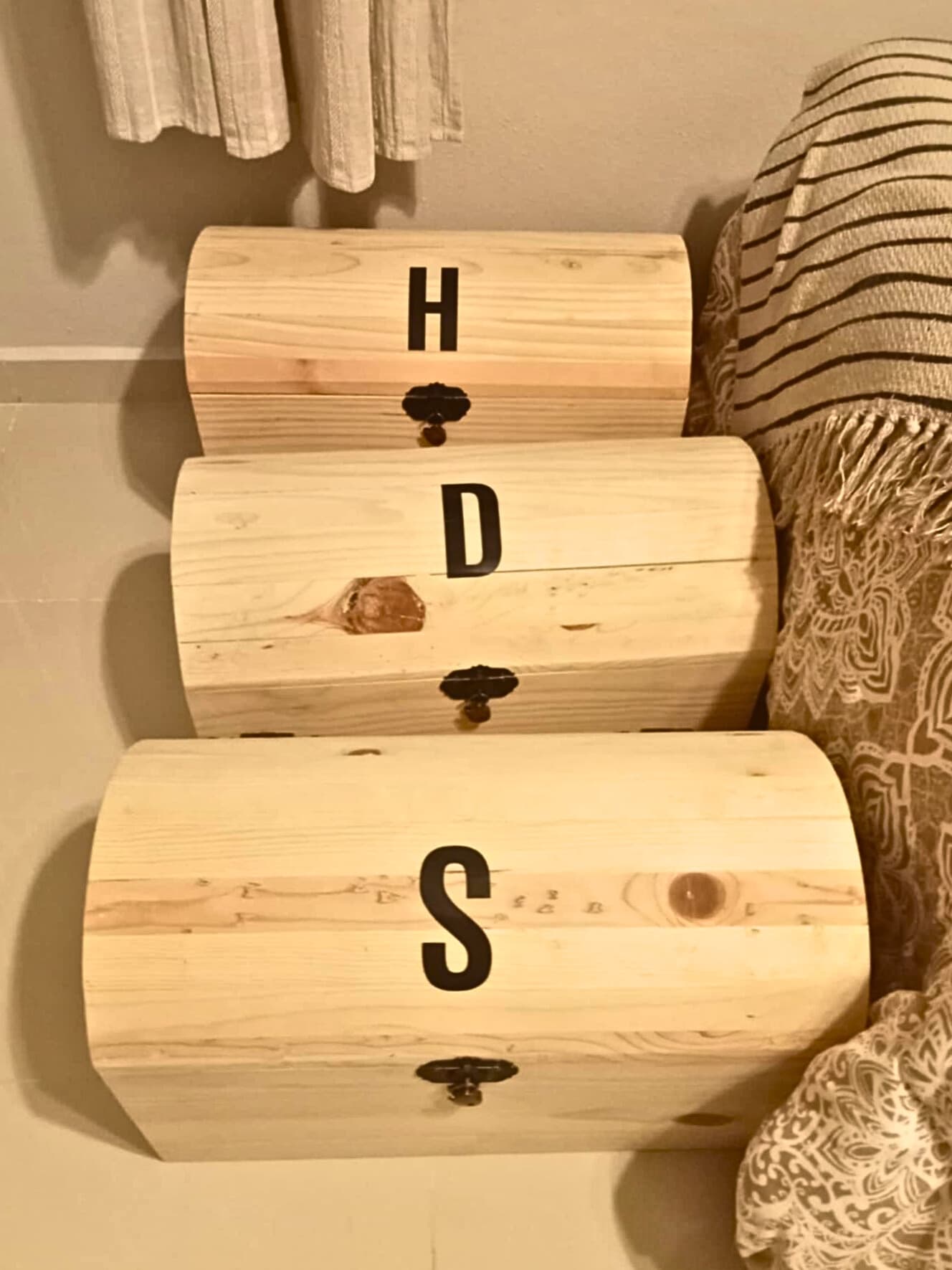 Three personalized wooden toy trunks with the letters H, D, and S